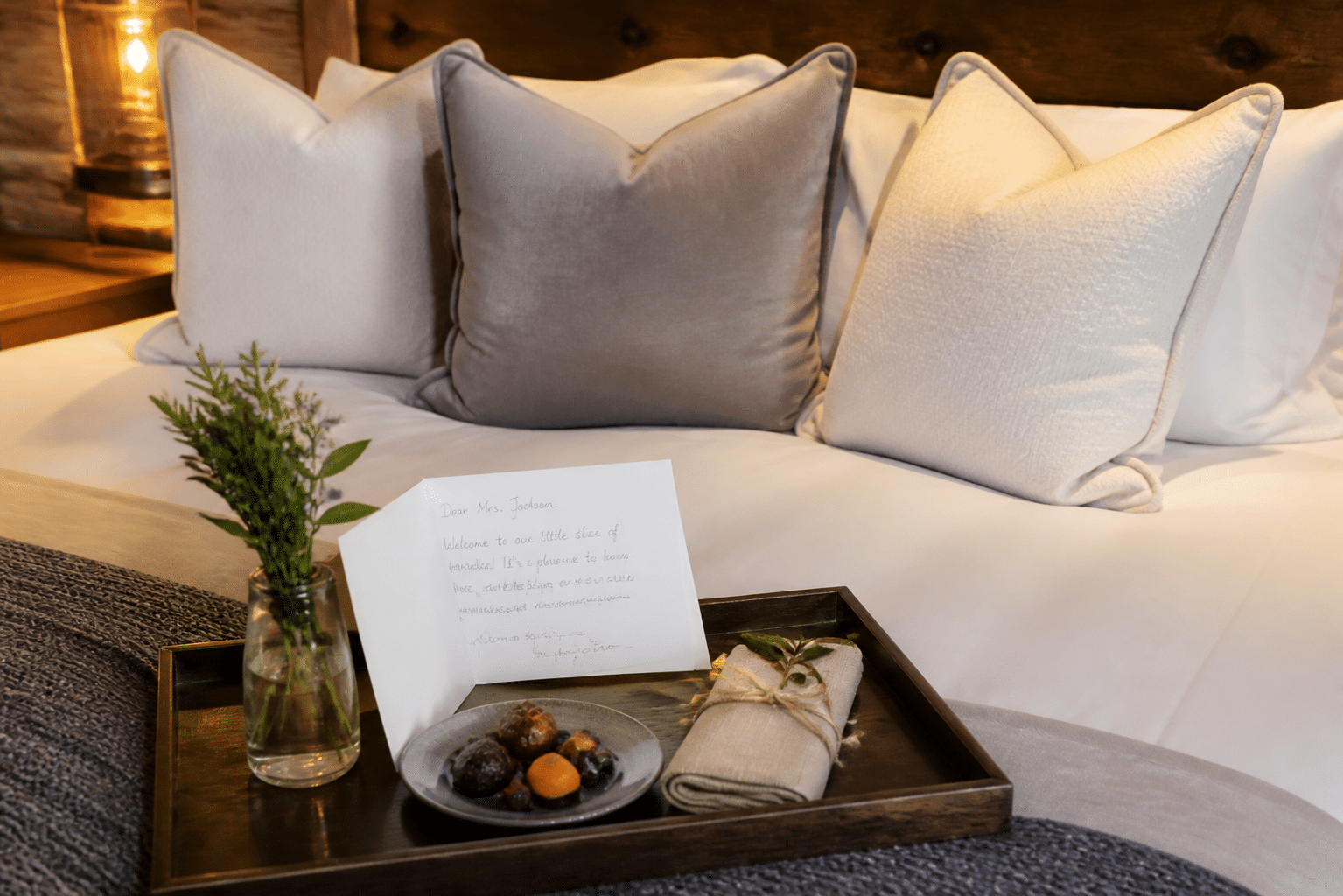 Personalized hotel room welcome featuring handwritten note, local artisan treats, and premium pillows