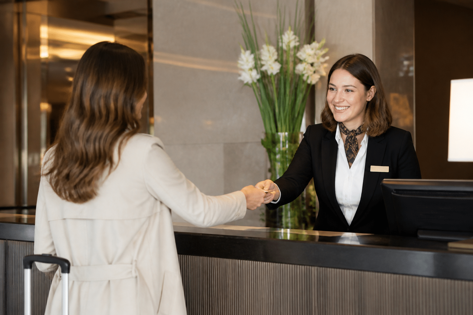 Hotel front desk professional warmly greeting guest during check-in process
