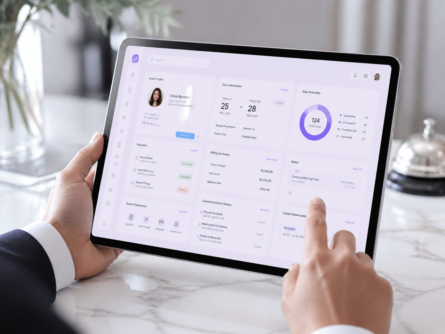 Hotel staff member using unified PMS dashboard on tablet to review guest information and preferences